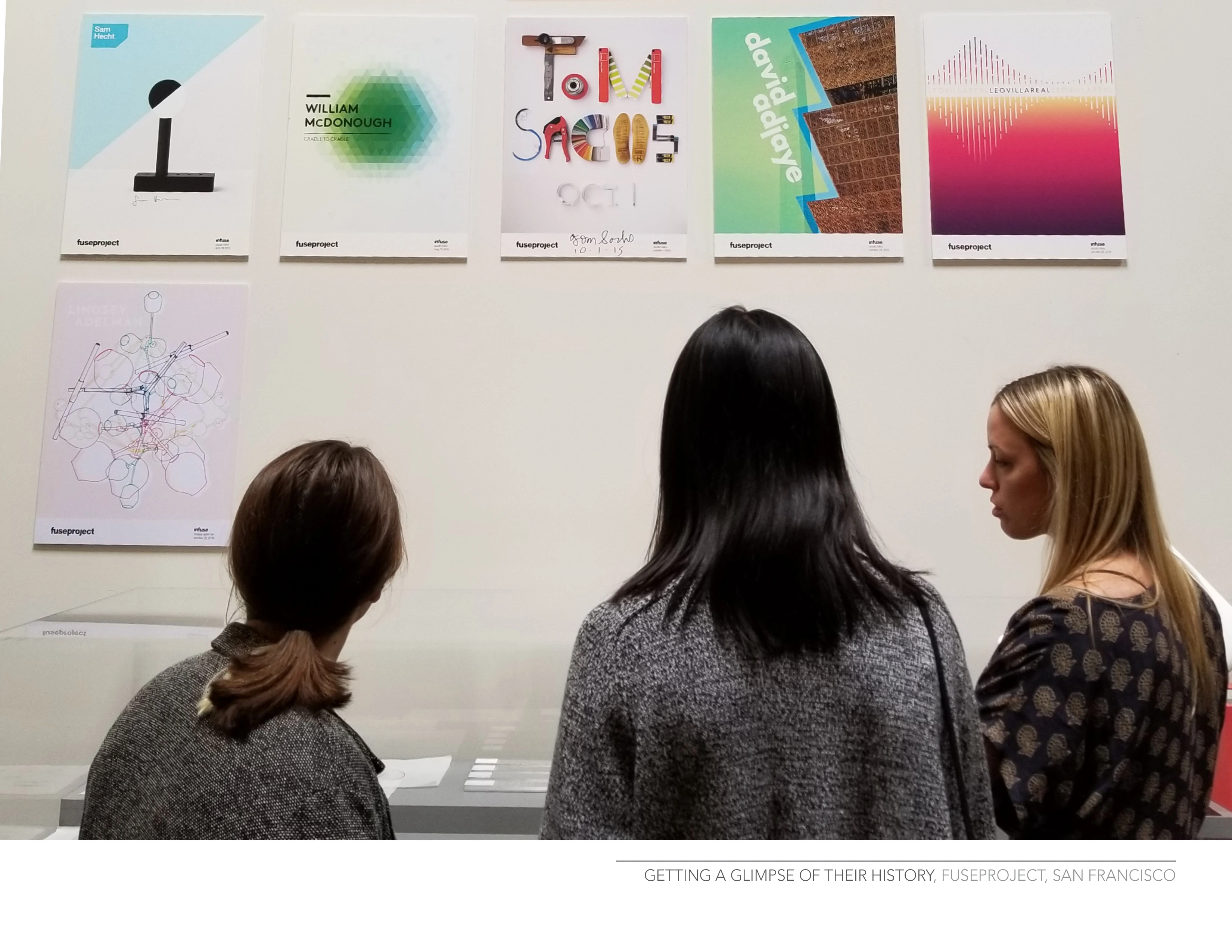 An image of designers looking at graphic design work on the wall.